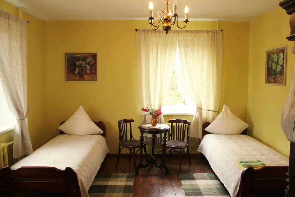 two beds in a room with a table and a window at Viesu nams Rūmes in Rēzekne