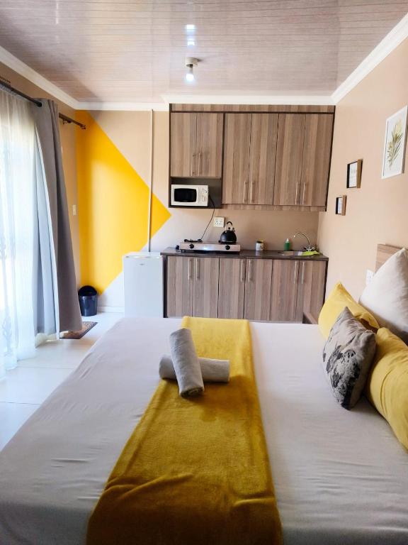 ein Schlafzimmer mit einem großen Bett und eine Küche in der Unterkunft Tokelo Guesthouse Emalahleni in Witbank