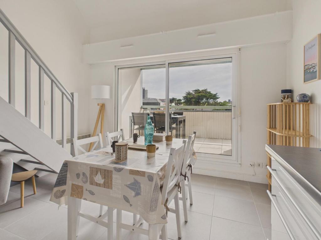 a dining room with a table and chairs and a window at Appartement avec piscine commune pour 4 in Guérande