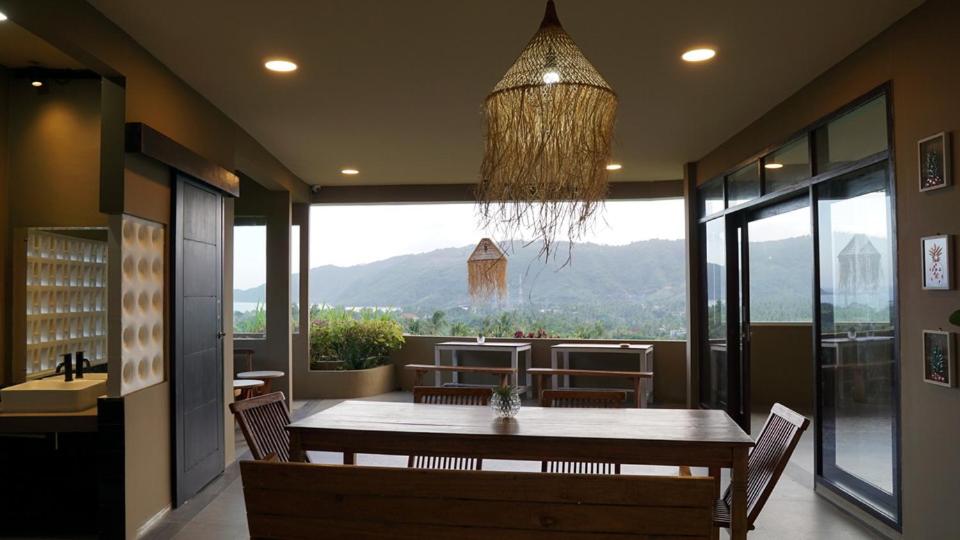 a dining room with a table and a large window at Lemon Hills Kuta in Kuta Lombok