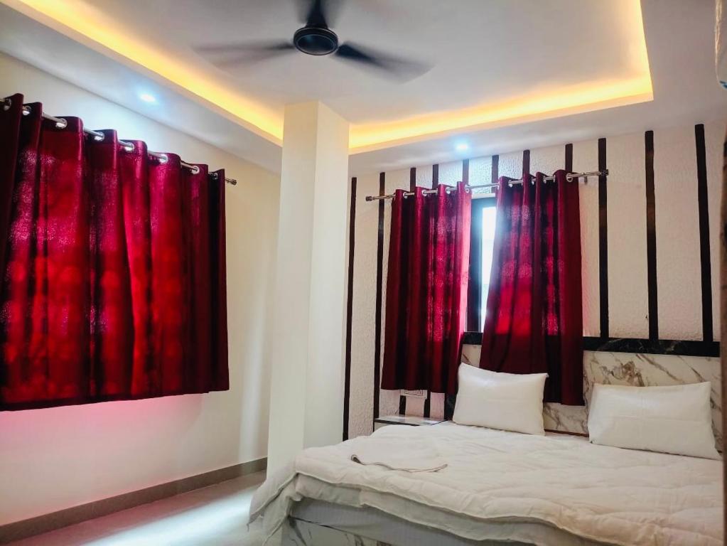 a bedroom with red curtains and a bed at Hotel Tara ji Bliss in Haridwār