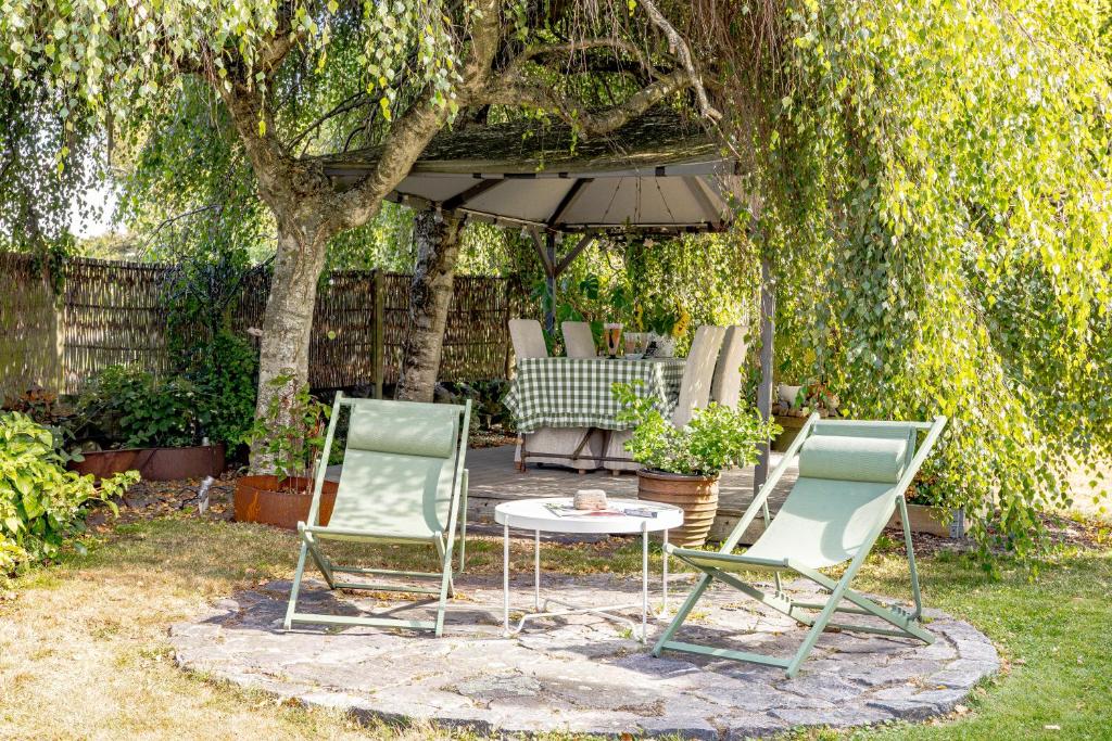 2 chaises et une table sous un parasol dans l'établissement Vacation Dream with Sea View, Sauna, Patio & BBQ, à Glommen