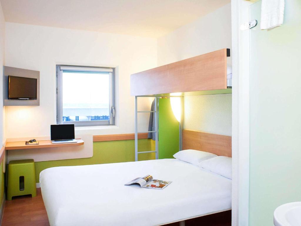 a bedroom with a bunk bed and a desk with a laptop at ibis budget Birmingham Airport Terminal Building - NEC in Bickenhill