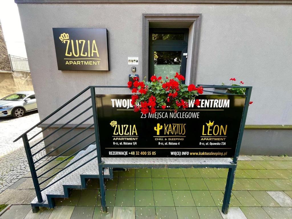 a sign in front of a restaurant with red flowers at Zuzia Apartment - 50 m od Rynku in Racibórz