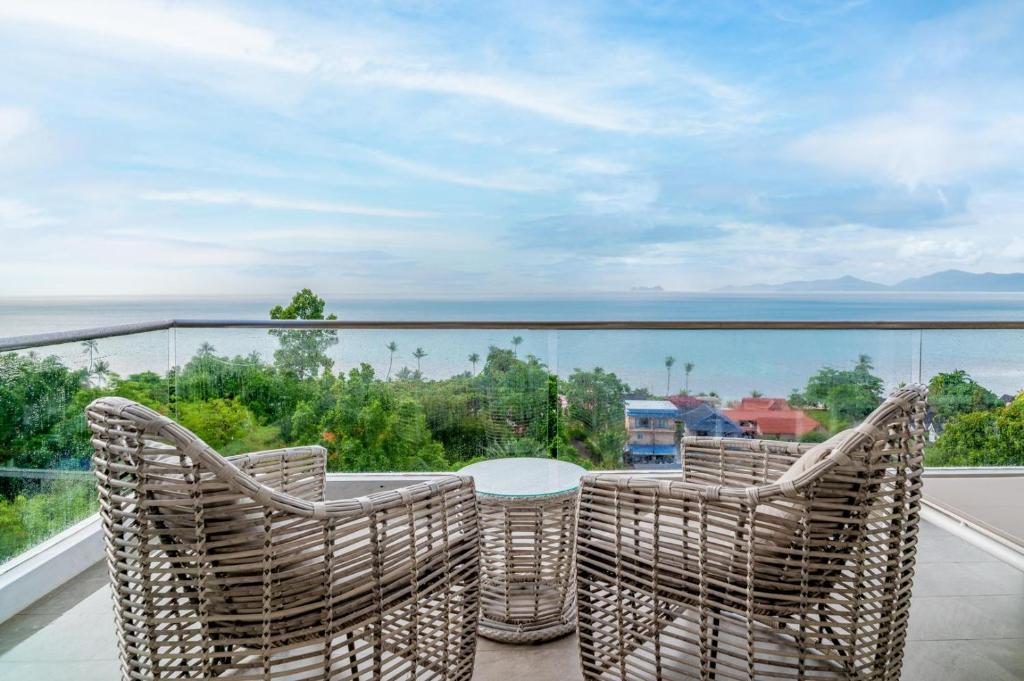 balcón con sillas de mimbre y mesa con vistas en Cozy 2-Bed Apt by the Sea Beach - KBR37, en Ban Bang Po