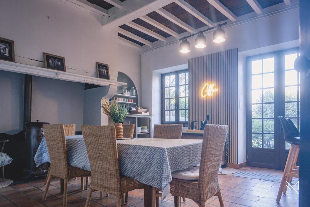 Gîte 4 étoiles, centre Monein, 4 chambres, terrasse, jusqu'à 8 pers في Monein: غرفة طعام بها طاولة وكراسي