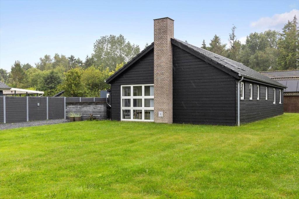 a black house with a grass yard in front of it at FY396-Middelfart-Siriusvej-4 in Middelfart