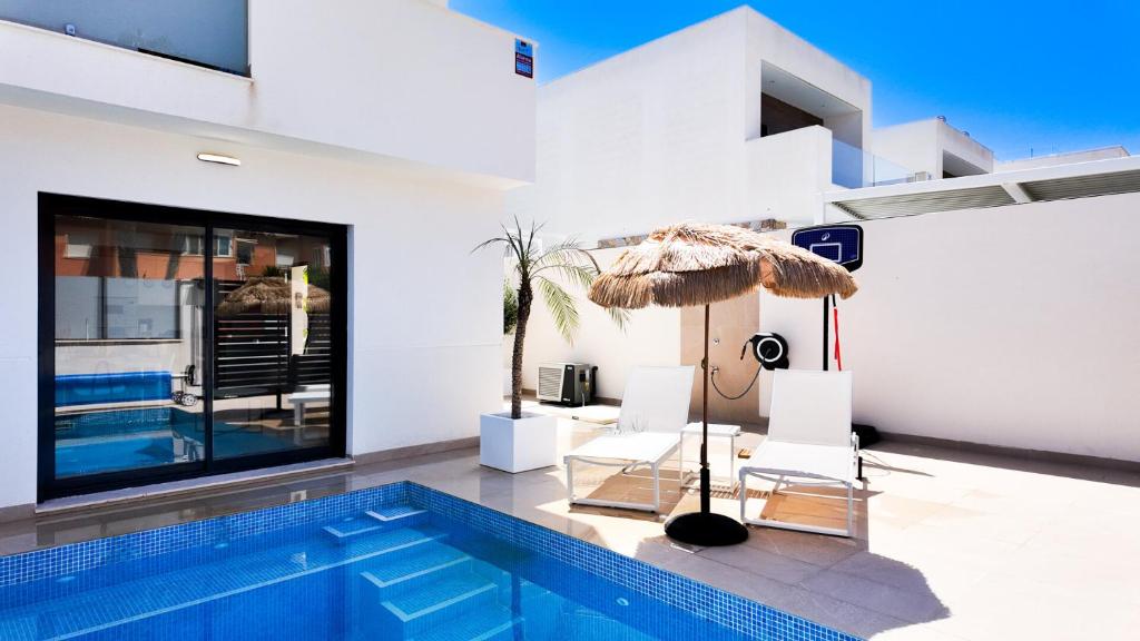 a swimming pool with two chairs and a umbrella at Villa Estrella del Mar in San Pedro del Pinatar