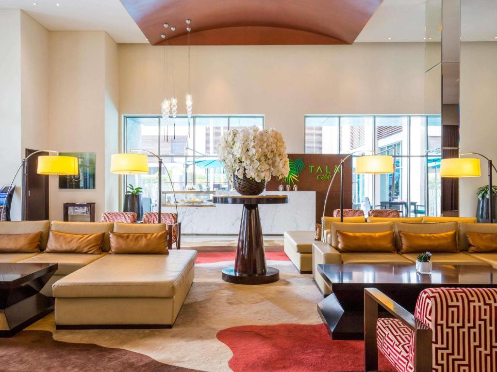 a lobby with couches and a table with a vase of flowers at Novotel Deira Creekside Dubai in Dubai