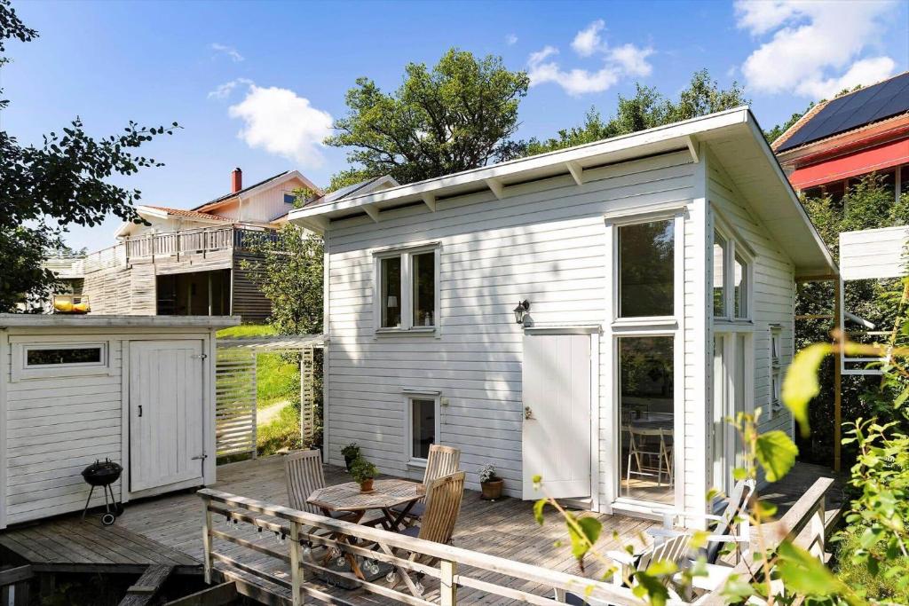 a small white tiny house with a wooden deck at BOH779-Stillingsoen-Asarna-121 in Åsarna