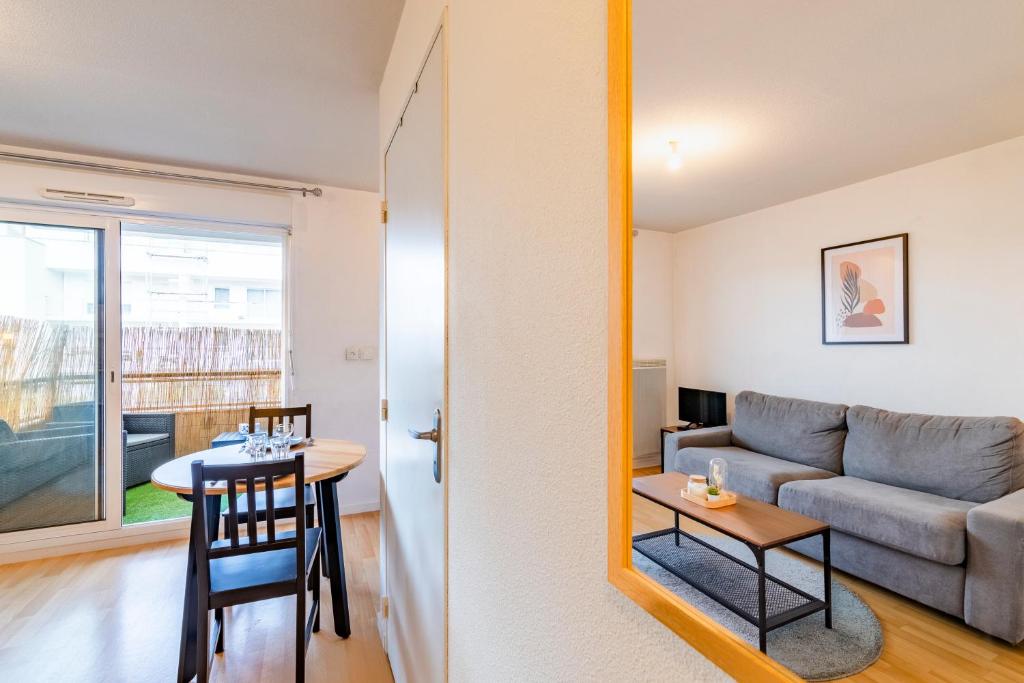 una sala de estar con un sofá y una mesa en Well-equipped studio with balcony, en Séné
