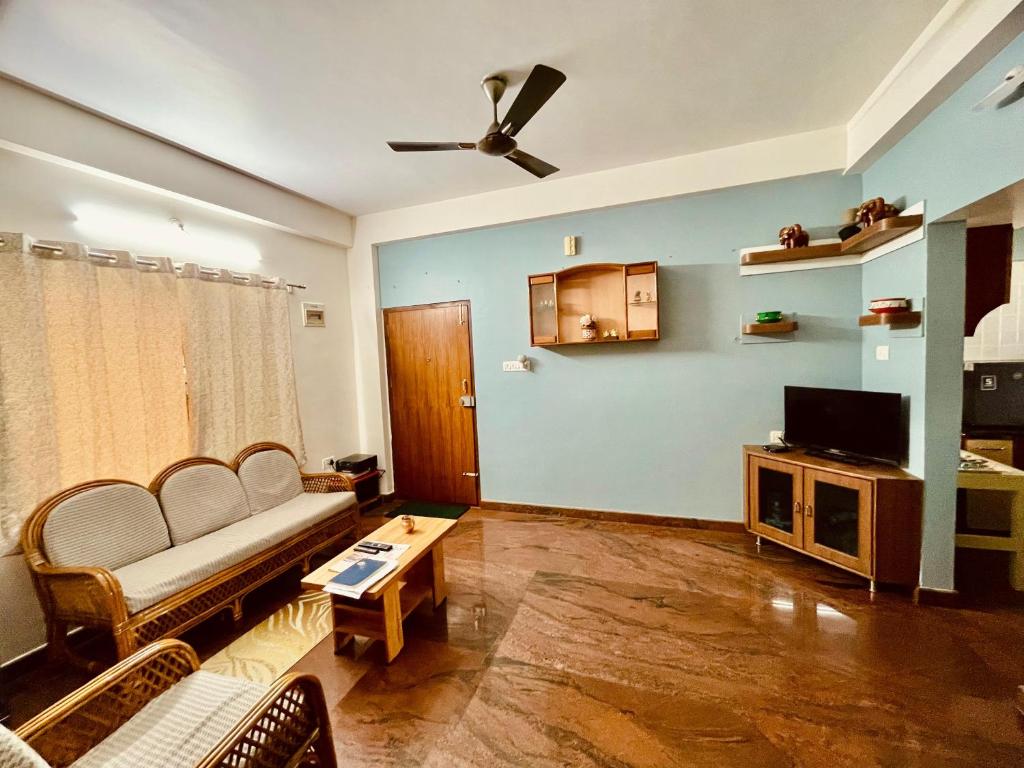 un soggiorno con un divano e una TV di Anand's Elegant 2BHK Apartment - AC a Mysore