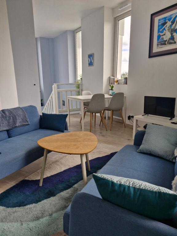 a living room with a blue couch and a table at Quiet duplex in historic town centre in Perros-Guirec