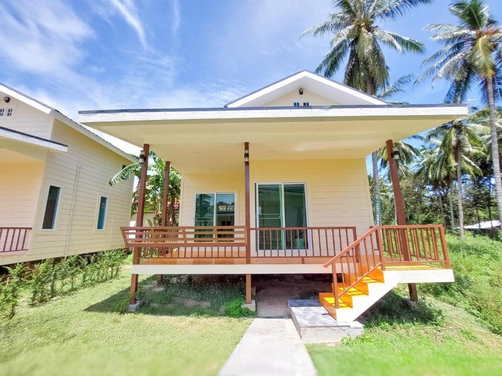 a house with a large wooden porch with palm trees at Billabong Village in Ko Phangan