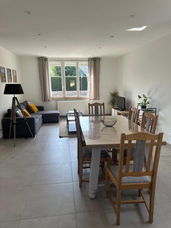 a dining room and living room with a table and chairs at Maison Le Refuge à 10 minutes de la Baie de Somme in Saint-Blimont