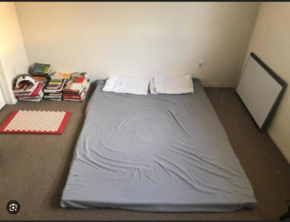 a small bed in a room with books on the floor at Mattis in Chennai