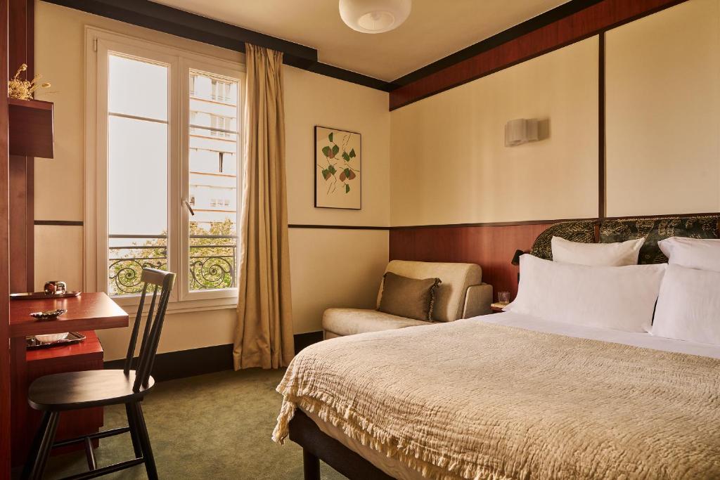 a bedroom with a bed and a chair and a window at Hôtel Marguerite in Paris