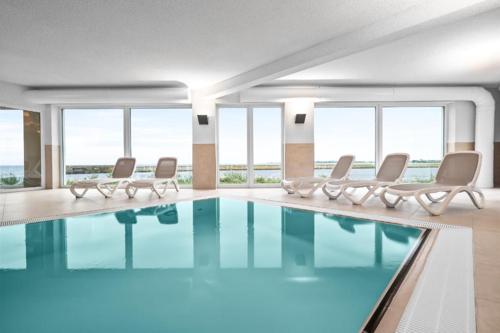 una camera d'albergo con piscina, sedie e finestre di Hafenspitze a Kappeln
