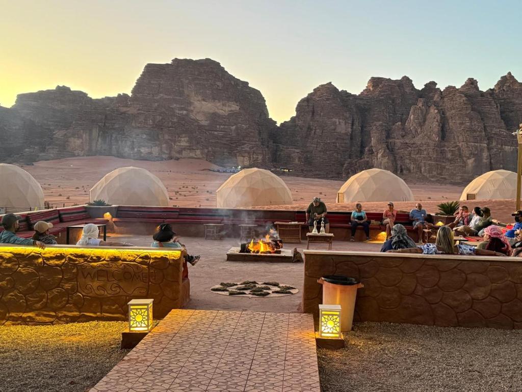 a group of people sitting around a fire in domes in a desert at Mira Rum Luxury Camp in Wadi Rum