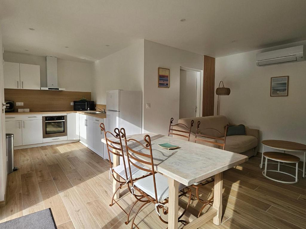 Appartement entouré de verdure في Saint-Martin-de-Seignanx: مطبخ وغرفة معيشة مع طاولة وكراسي