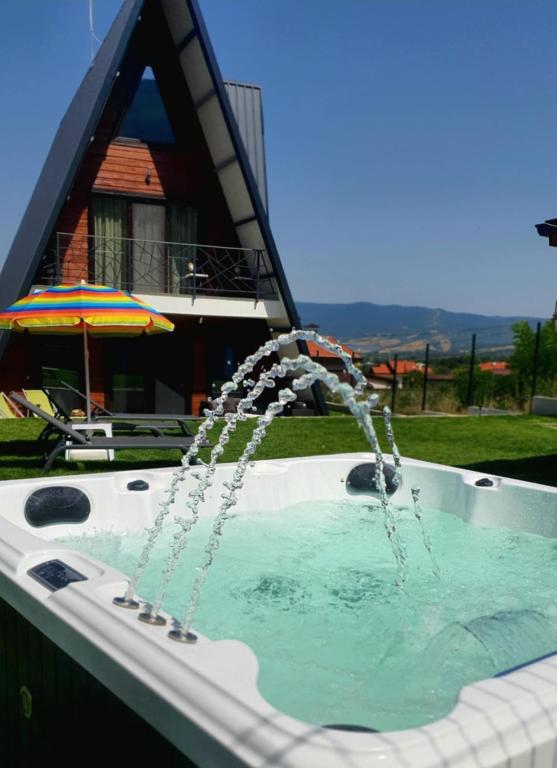 a water fountain in a swimming pool with a house at Magnika in Sapareva Banya
