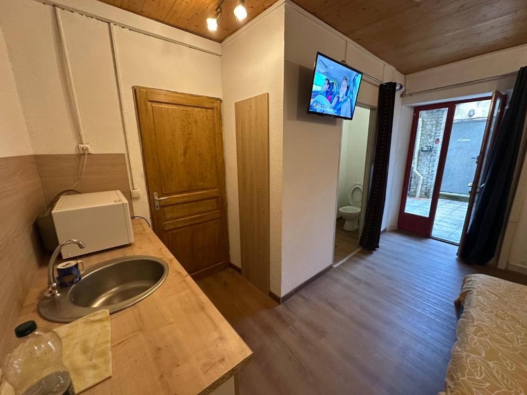 a bathroom with a sink and a tv on the wall at Imprevu in La Voulte-sur-Rhône