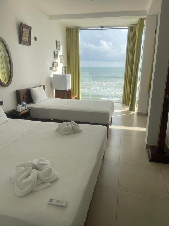 two beds in a hotel room with a view of the ocean at KINGS BAY Beach Resort in Galle