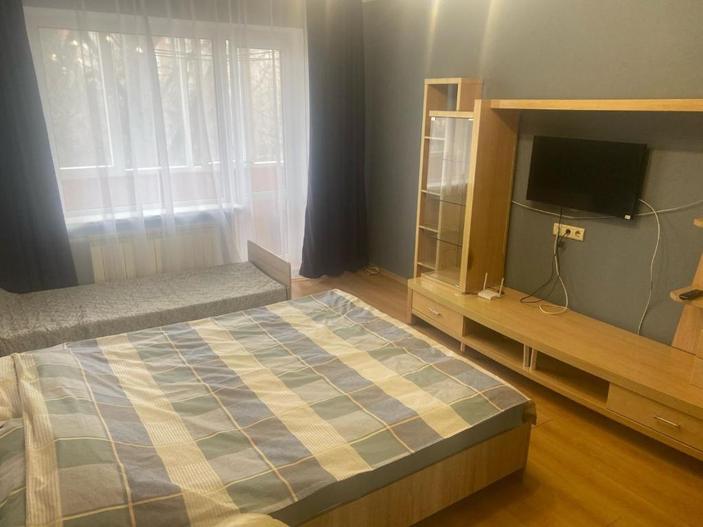 Un dormitorio con una cama y un televisor en un estante. en Чудова квартира біля ТРЦ Лавина, en Sumy
