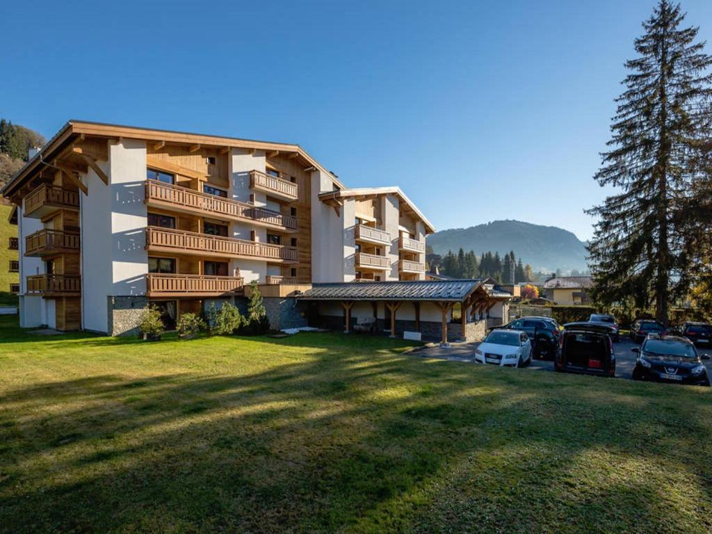 a large building with cars parked in a parking lot at Résidence Hôtel Rent - Megève in Megève