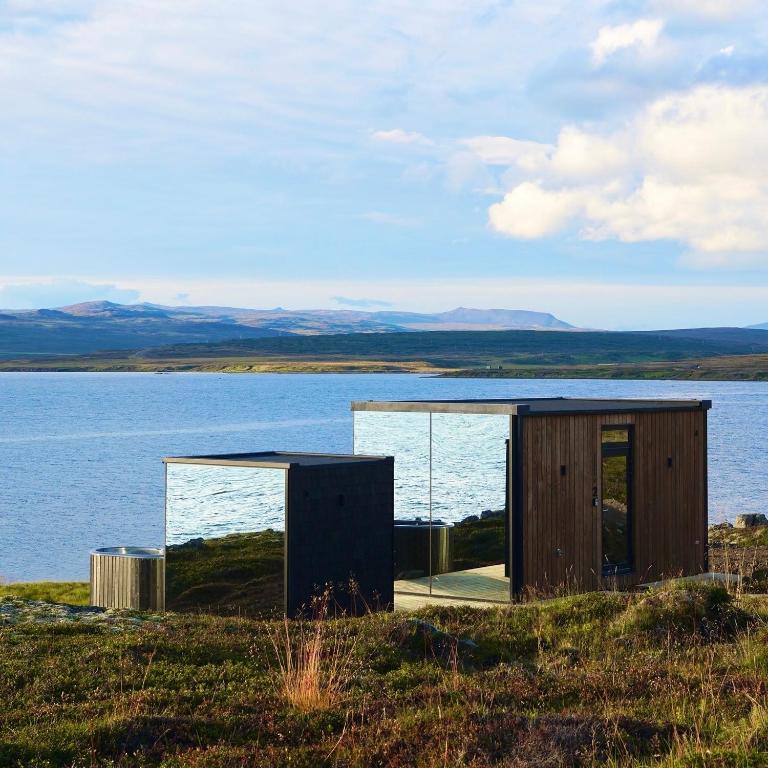 a house on top of a hill next to a body of water at Mirror Suite in Hjarðarholt