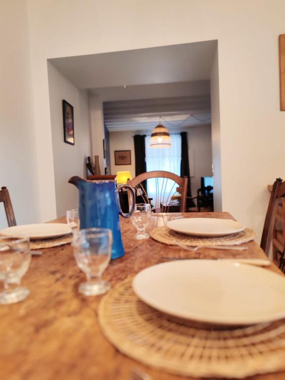a wooden table with plates and glasses on it at Maison chic du Jerzual in Dinan