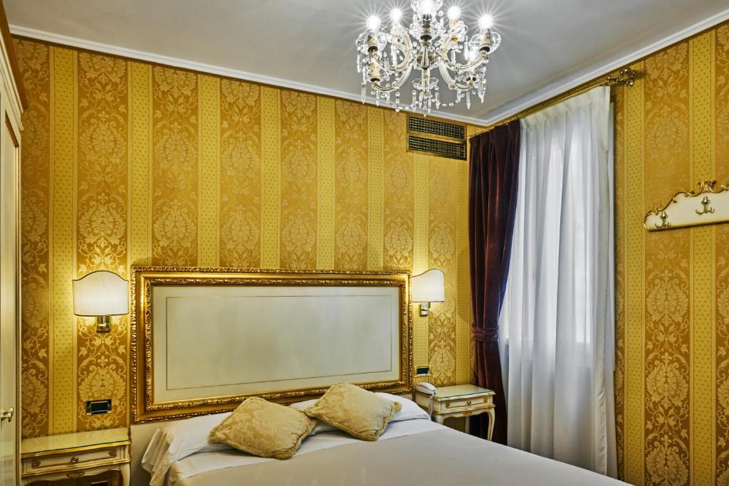a bedroom with a bed and a chandelier at Hotel Gardena in Venice