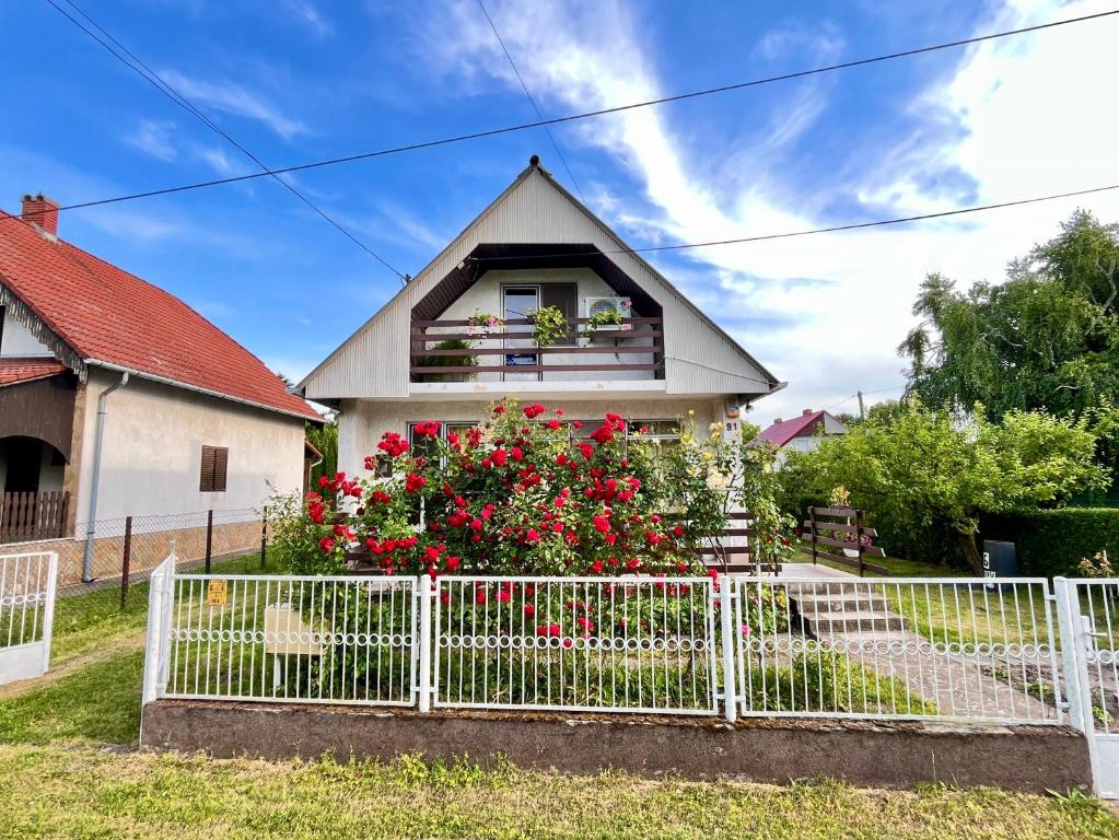 a white fence in front of a house with flowers at János Nyaraló in Balatonmáriafürdő