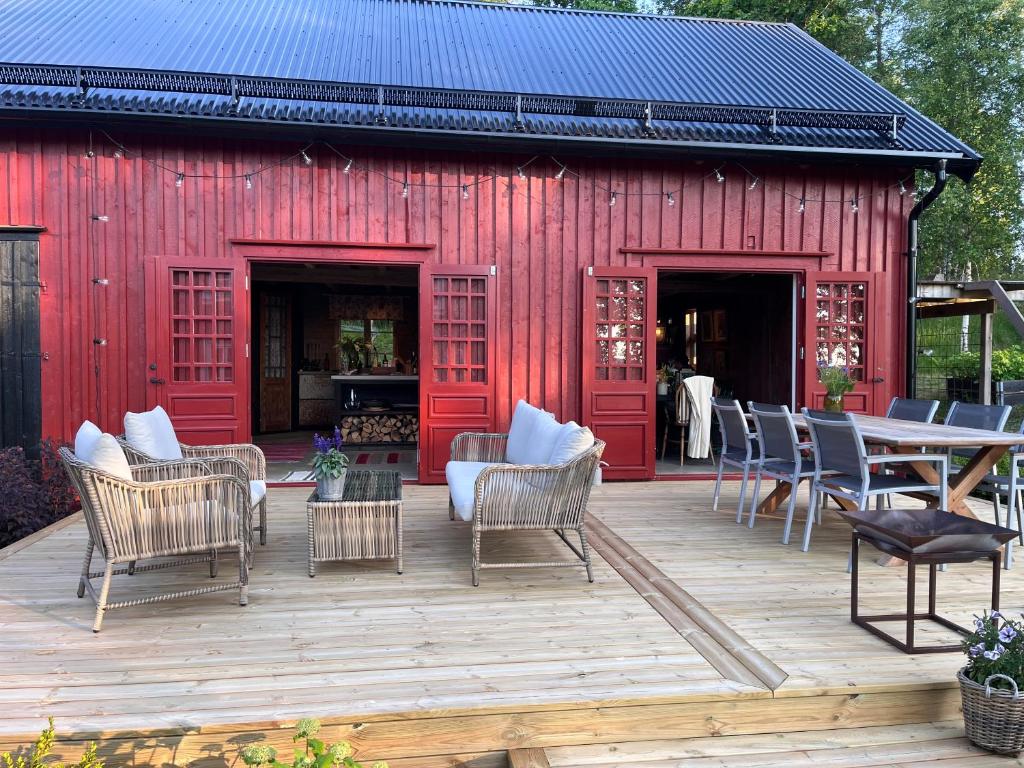 a red building with chairs and a table on a deck at Kyrkliden in Torestorp