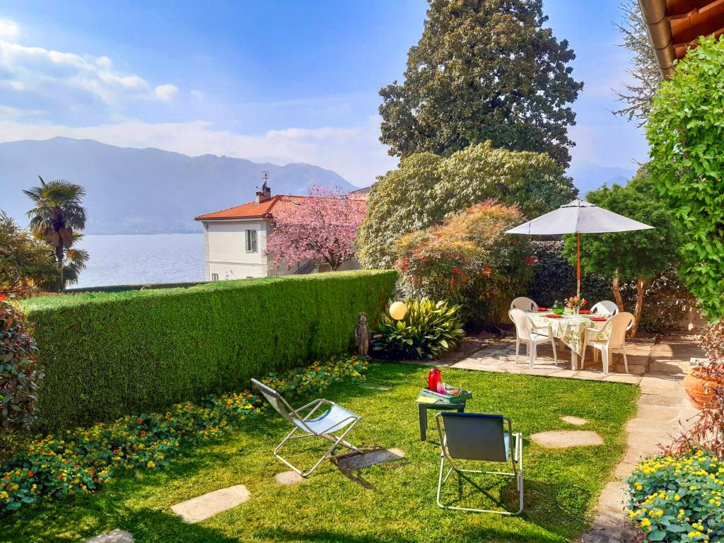 un jardín con mesa, sillas y sombrilla en Villino Alborella, en Verbania