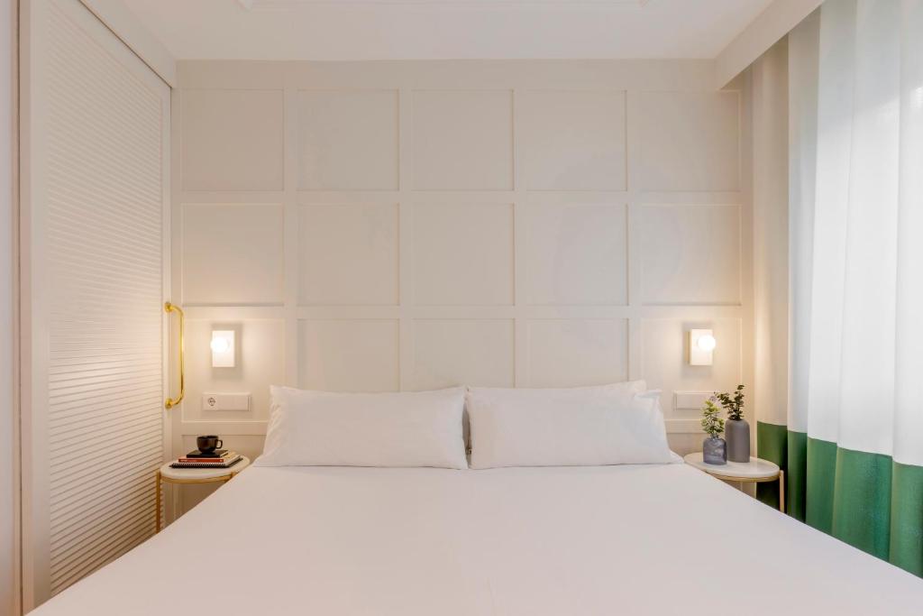 a bedroom with a large white bed with white walls at Room Mate Cosmo - City Centre, Valencia in Valencia