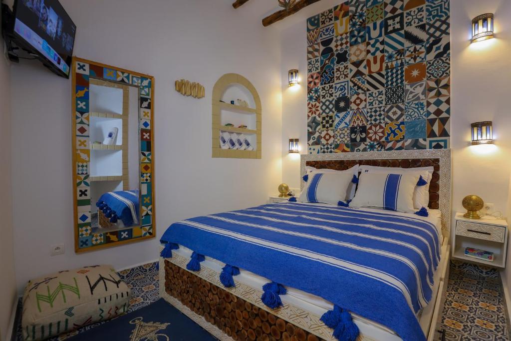 a bedroom with a blue and white bed and a tv at Riad dar HAPPY NOCHE in Essaouira