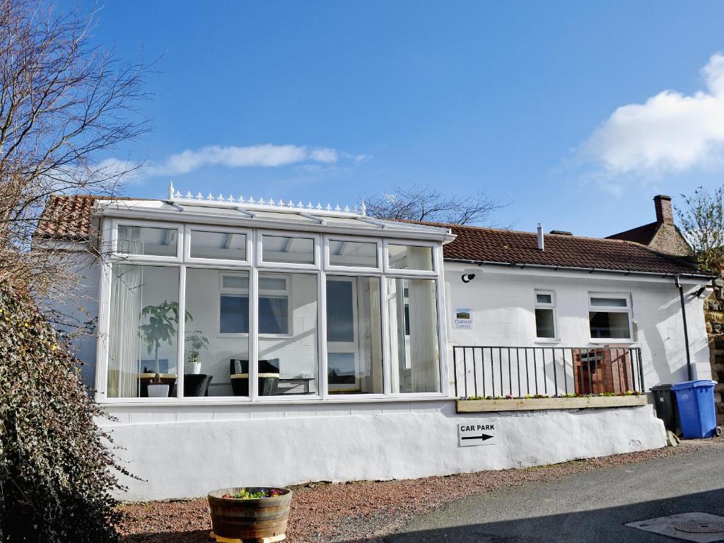 a white house with a large conservatory on it at Cheviot Cottage in Belford