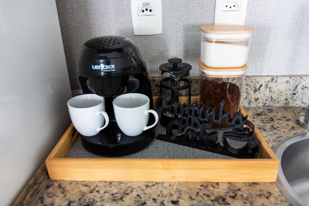 a coffee maker and two cups on a wooden tray at Flat Alto Padrão no Saint Moritz - Localização Central e Wi-Fi Rápido in Brasilia