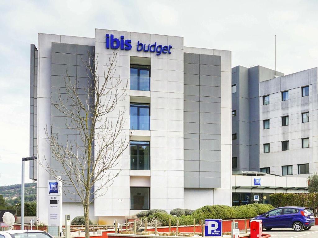 un edificio con un cartello con un secchio per autobus sopra di Ibis Budget Girona Costa Brava a Girona