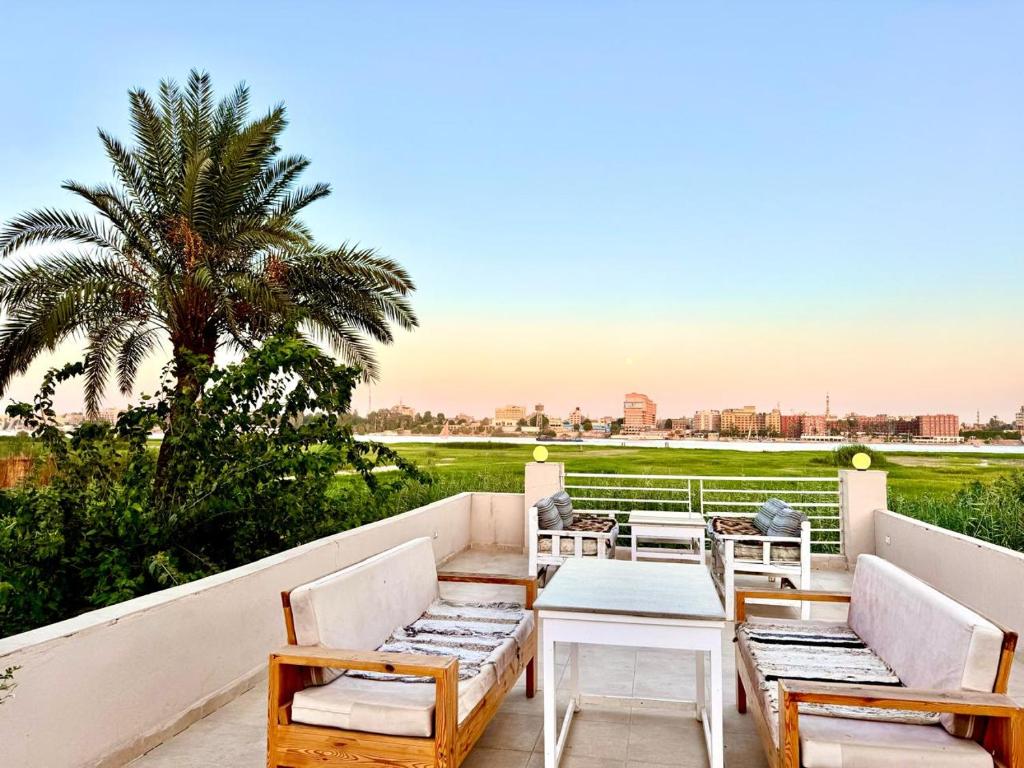 une terrasse avec des chaises, une table et un palmier dans l'établissement Royal Nile Villa - Luxury Nile Sky Penthouse 1, à Al Aqālitah