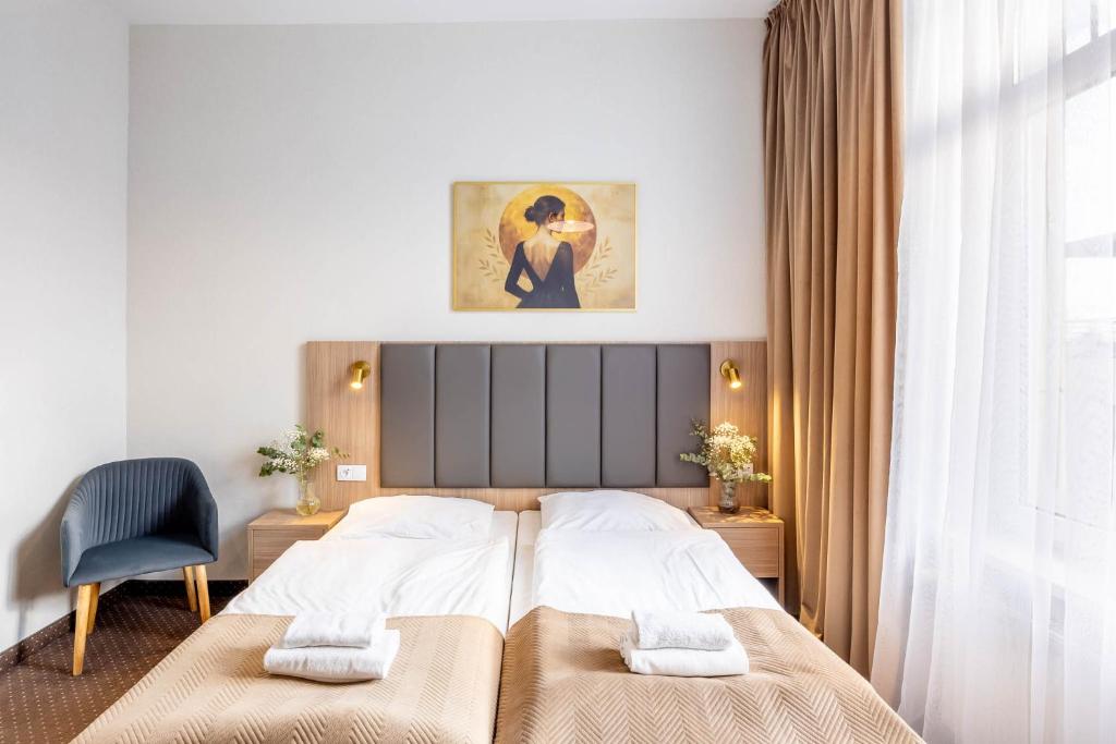 a bedroom with a bed and a chair and a window at Hotel Lothus in Wrocław