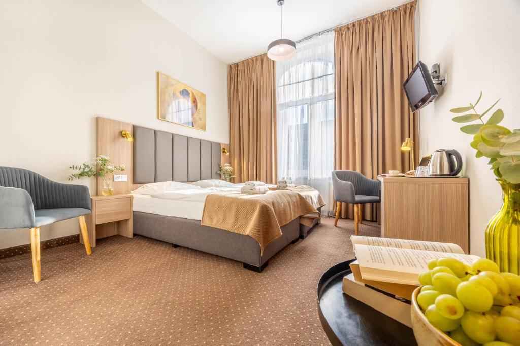 ein Hotelzimmer mit Bett, Tisch und Stühlen in der Unterkunft Hotel Lothus in Breslau