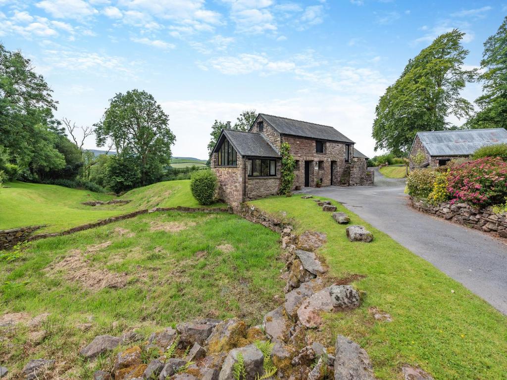 an old stone house on a hill with a road at Ty Nant-Oxl in Gwynfe