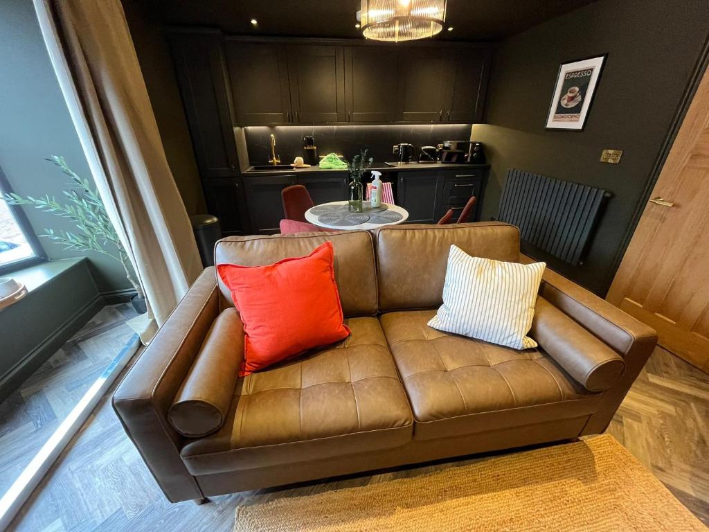 a brown couch with two pillows on it in a living room at The Hideaway Bureau - Lowlands in Wooler