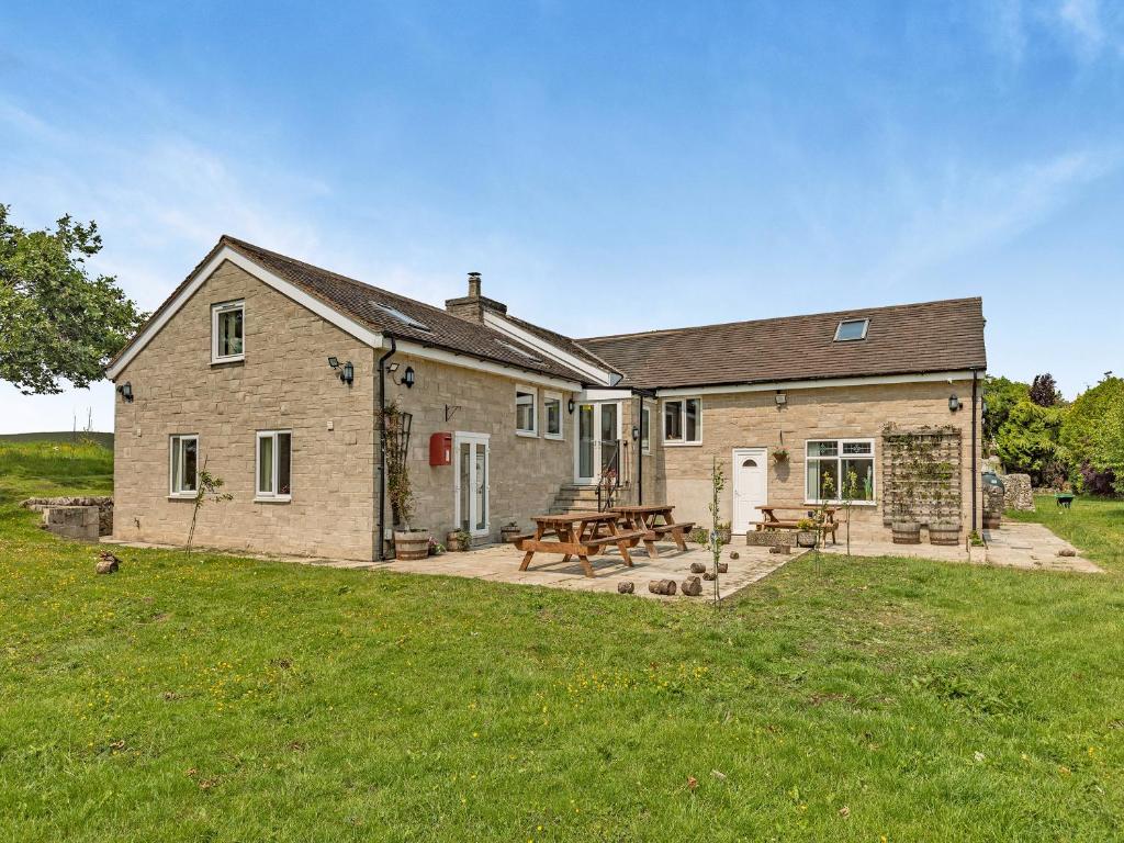 a large stone house with a picnic table and benches at Greystones Nawab Annex C in Monyash