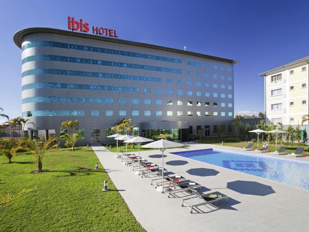 un hotel con sillas y sombrillas frente a una piscina en Ibis Antananarivo Ankorondrano, en Antananarivo