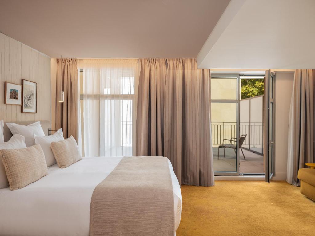 a bedroom with a large white bed and a balcony at Hôtel Saint Christophe Aix en Provence Centre Ville by Germain Collection in Aix-en-Provence