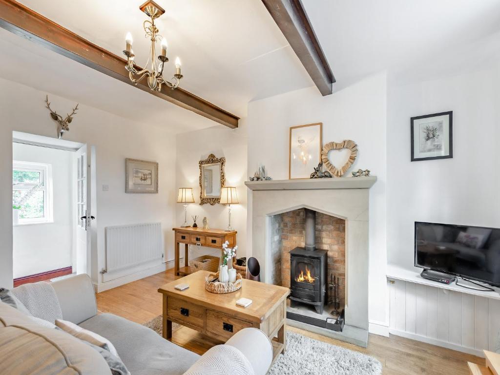 a living room with a fireplace and a tv at Holme House Cottage in Oakworth
