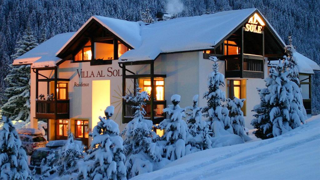 a house covered in snow with lights on at Residence Villa al Sole in Selva di Val Gardena